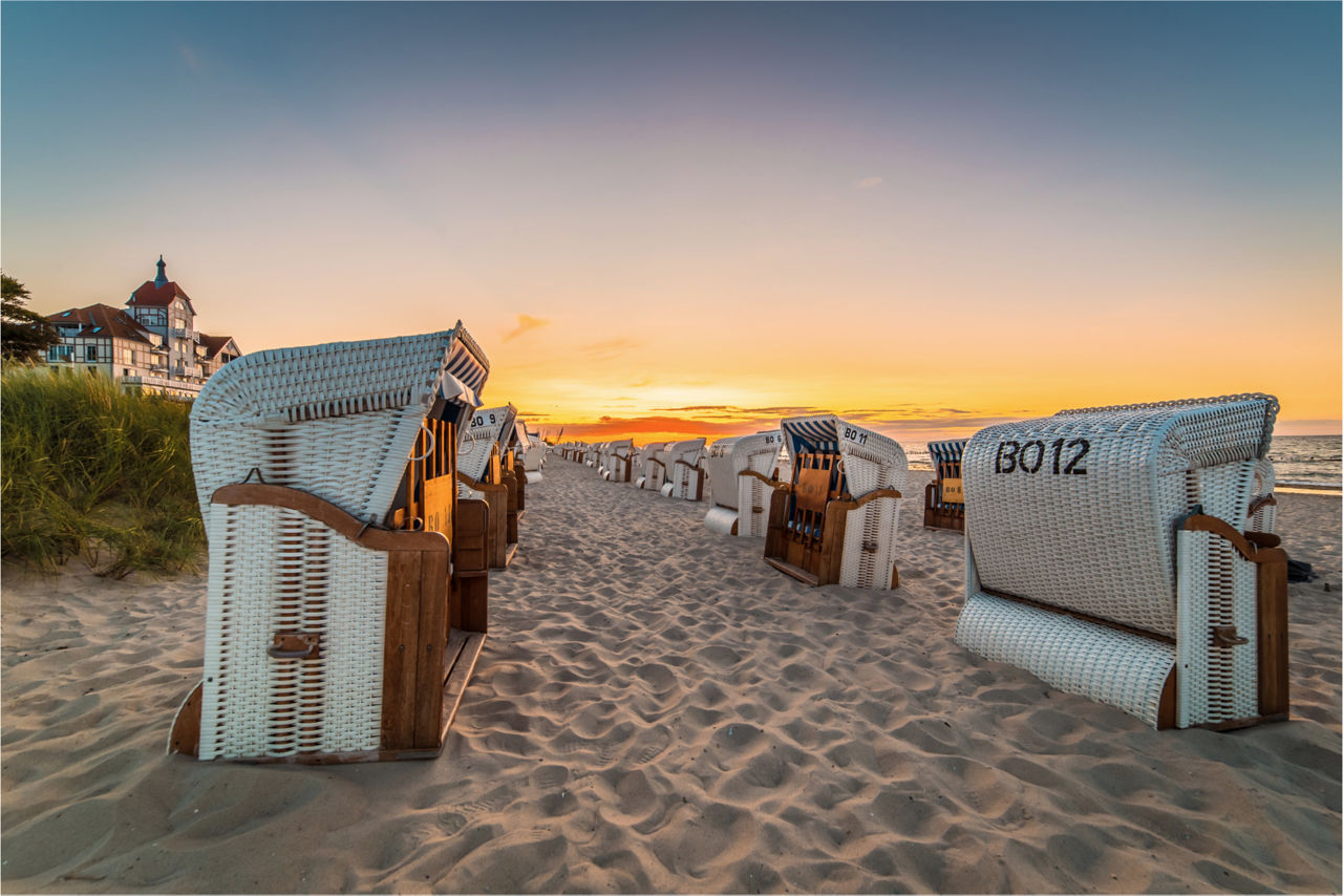 Eine Reihe Strandkörbe am Strand mit Sonnenuntergang.