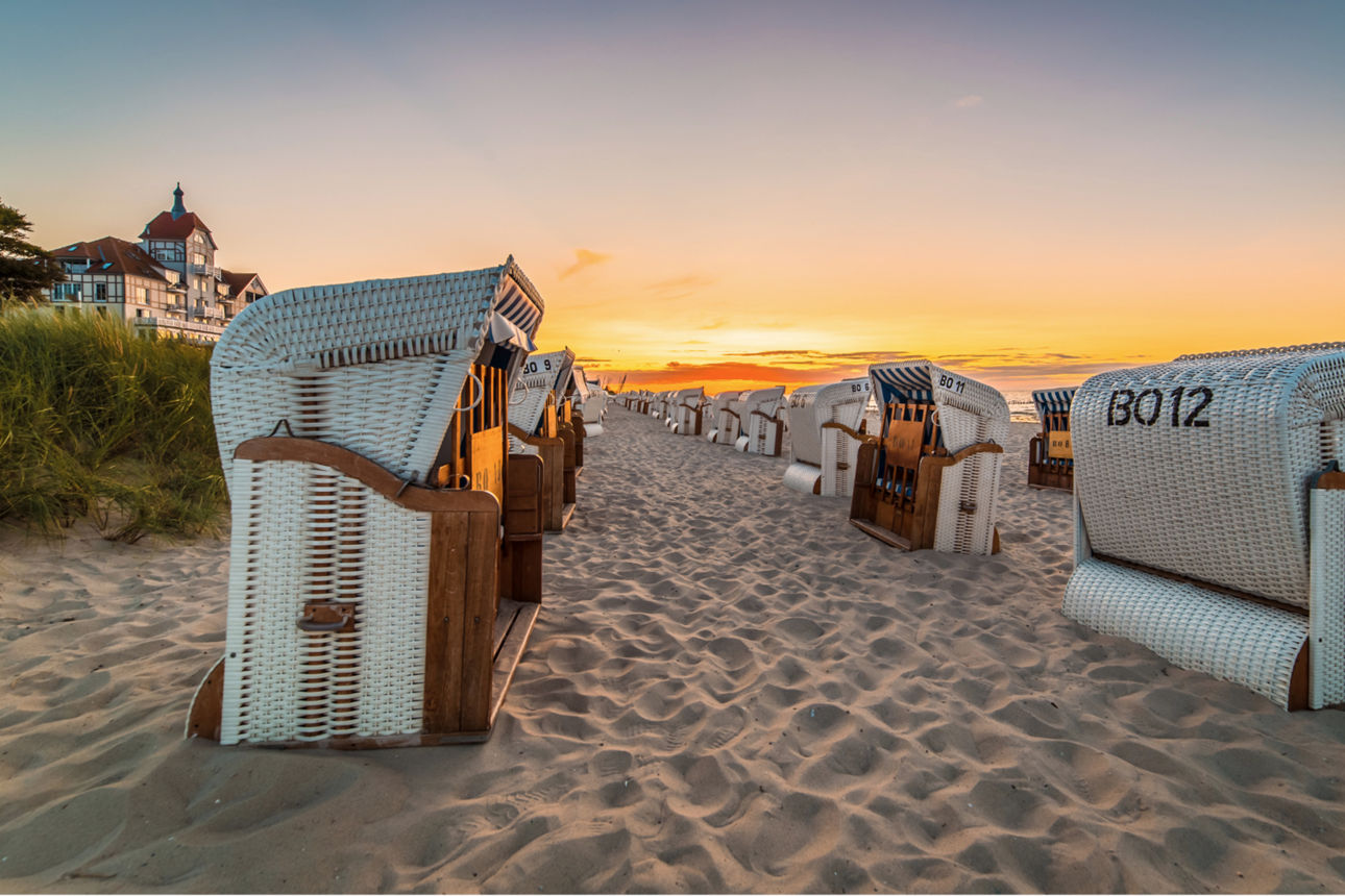 Eine Reihe Strandkörbe am Strand mit Sonnenuntergang.