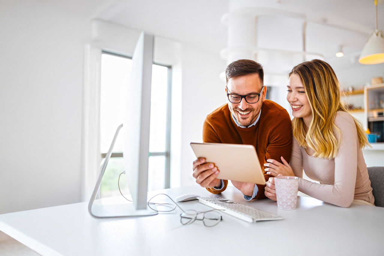 Mann hat Tablet-PC in der Hand, Frau schaut auf das Display