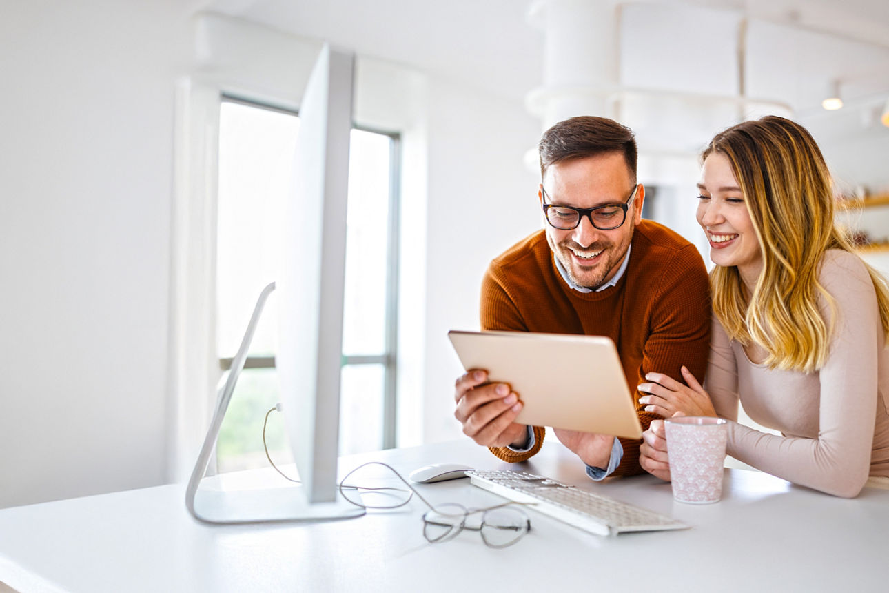 Mann hat Tablet-PC in der Hand, Frau schaut auf das Display