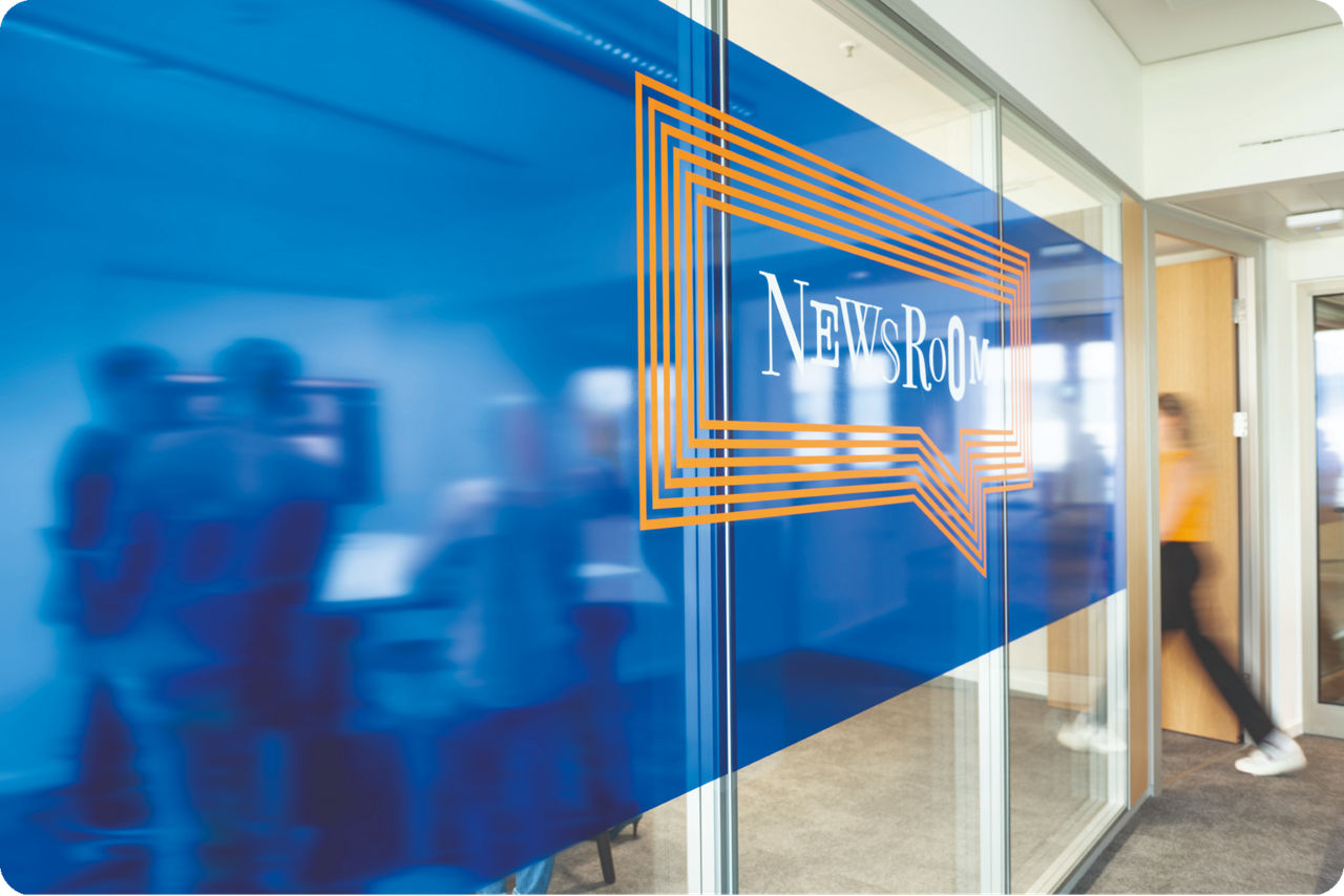 Ein Raum mit Menschen auf dem Newsroom steht
