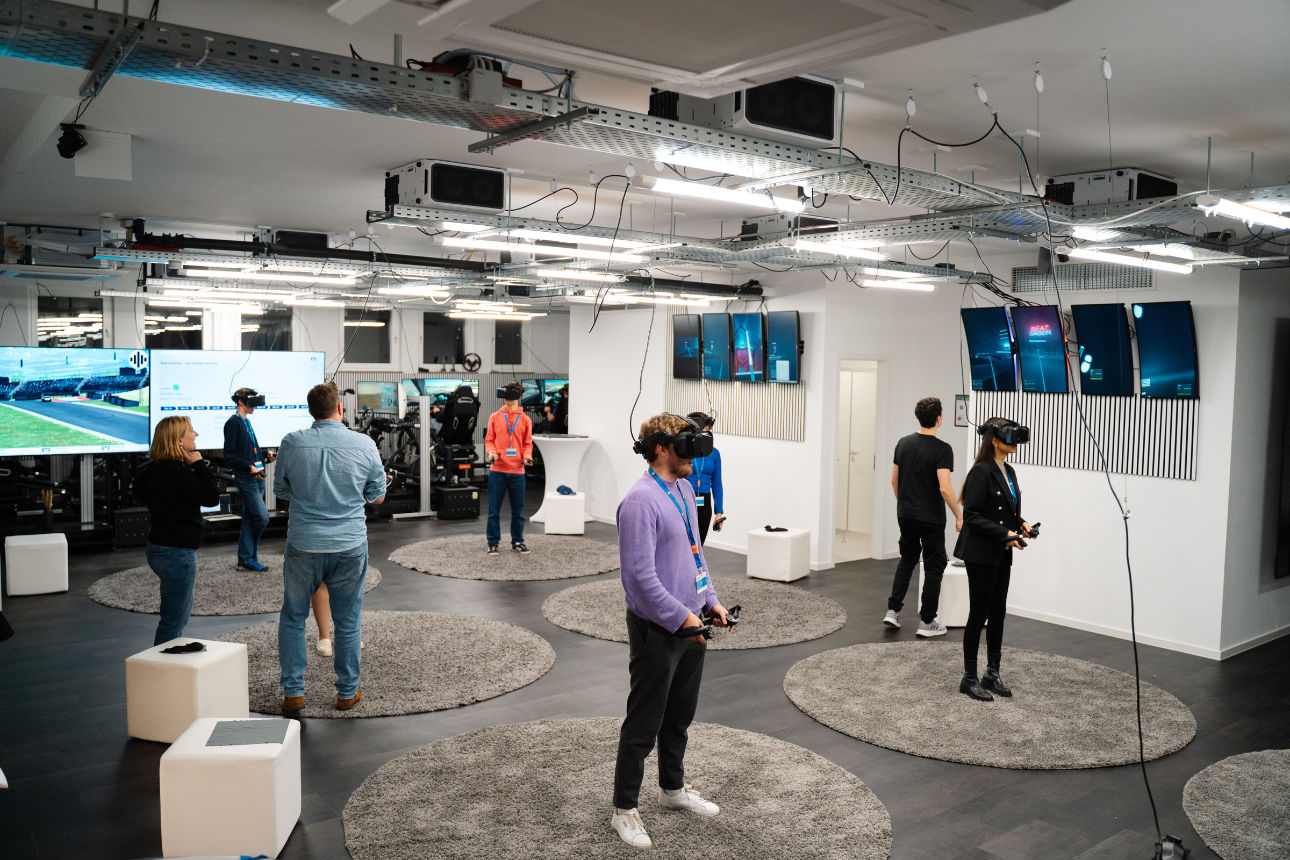 Mehrere Personen erkunden einen VR‑Raum und tragen Virtual‑Reality‑Brillen und Controller.