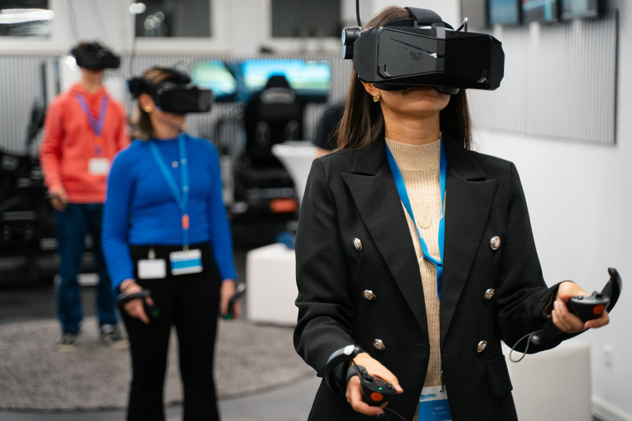 Personen nutzen VR‑Brillen und Controller in einem Technikraum mit mehreren Monitoren.