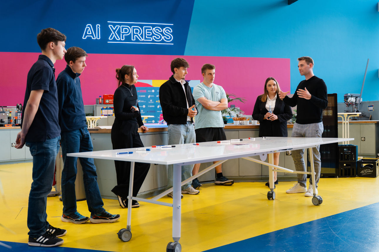 Gruppe von Personen bei Workshop im AI-XPRESS-Labor, diskutiert Ideen an mobilem Whiteboard.