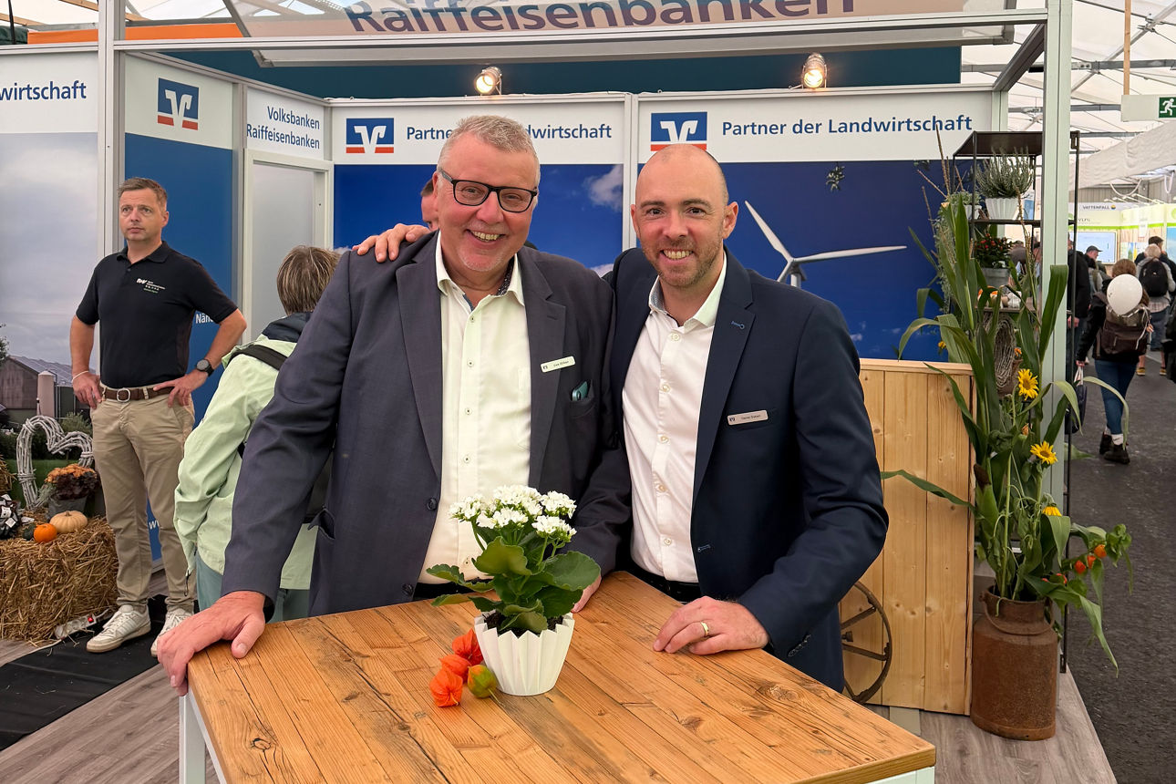 Zwei Männer stehen vor dem Volksbanken Raiffeisenbanken Messestand auf der Norla. 