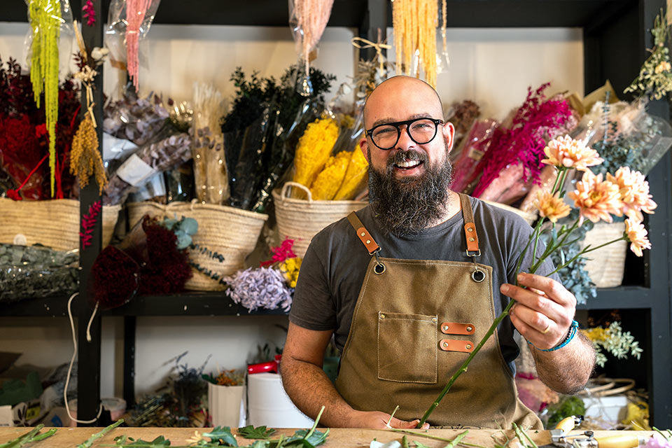 Drei Freunde mit Sonnenbrillen sitzen im Freien und schauen gemeinsam auf ihre Smartphones.