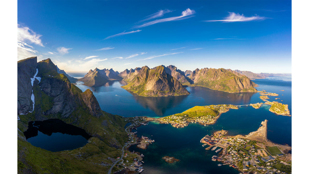 Dramatische Luftaufnahme der Lofoten: Zerklüftete Berge, tiefblaue Fjorde und Fischerdörfer.