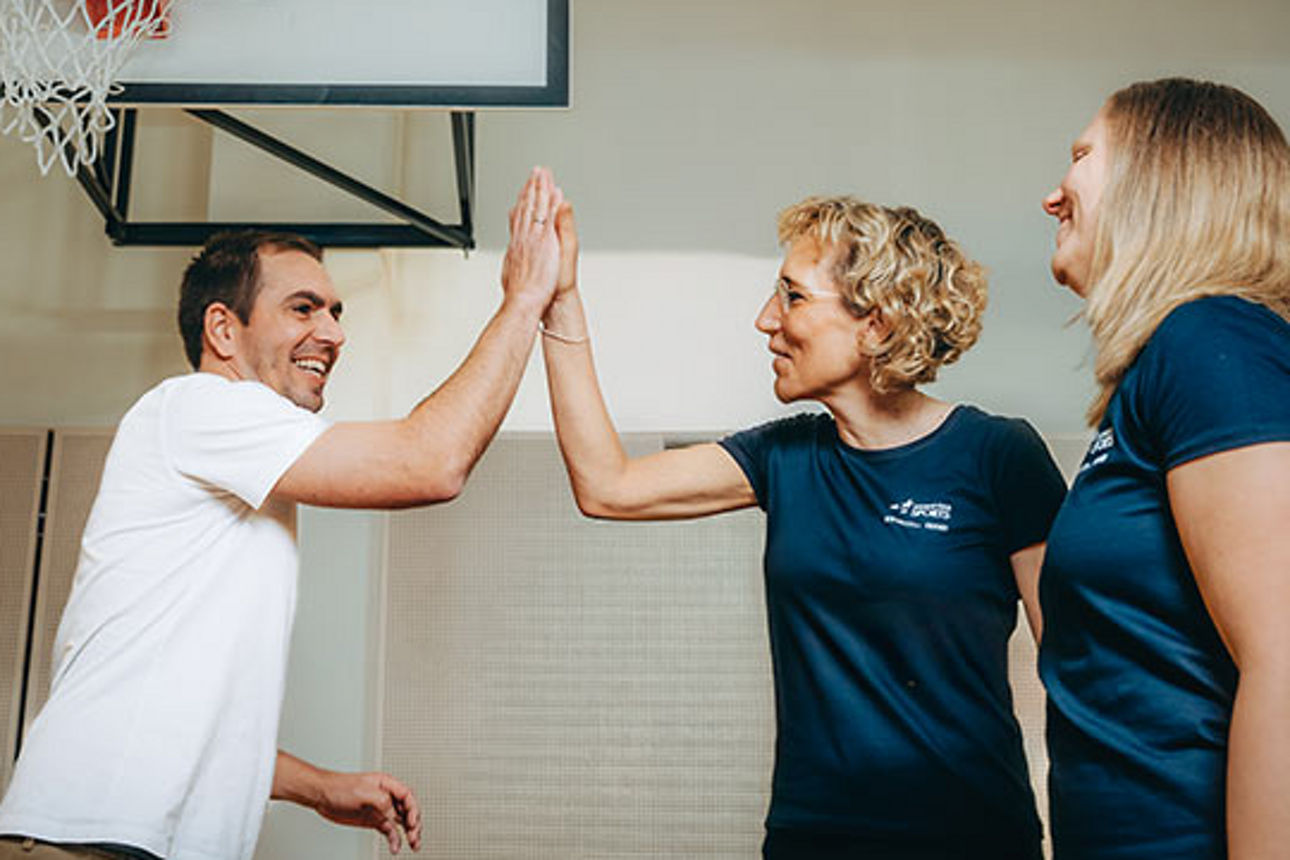 Philipp Lahm gibt einer Frau in einer Sporthalle ein High Five