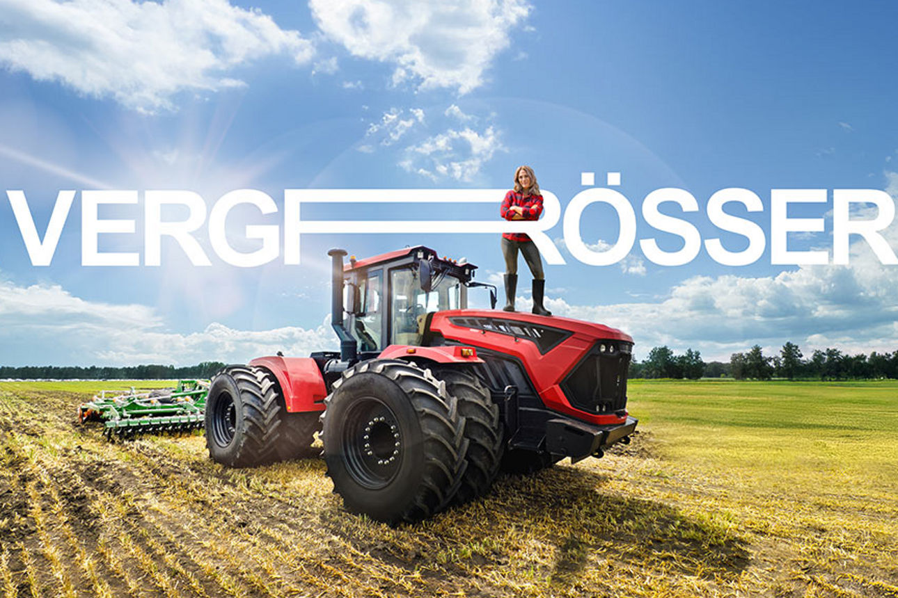 Eine Landwirtin posiert mit verschränkten Armen auf einem großen Traktor, der mitten auf einem Acker steht