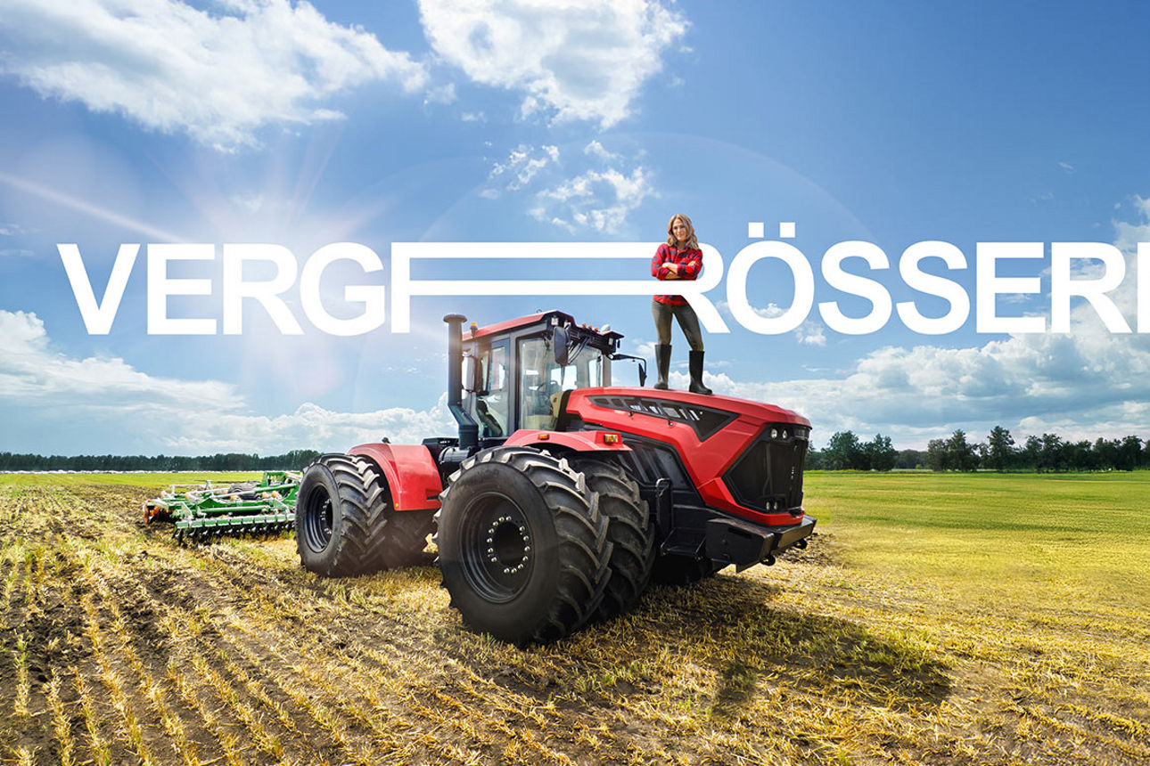 Eine Landwirtin posiert mit verschränkten Armen auf einem großen Traktor, der mitten auf einem Acker steht