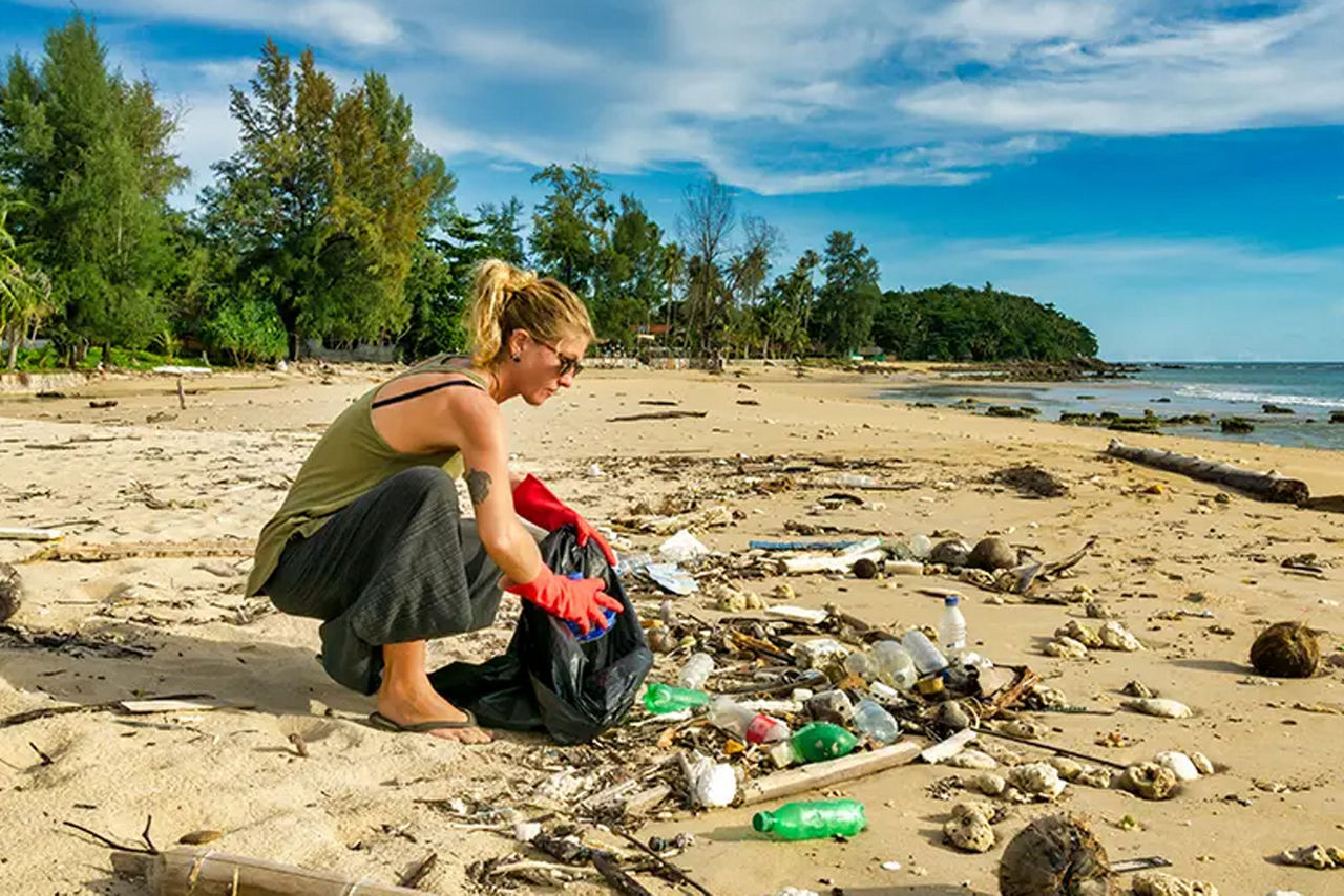 Frau sammelt Müll am Strand auf