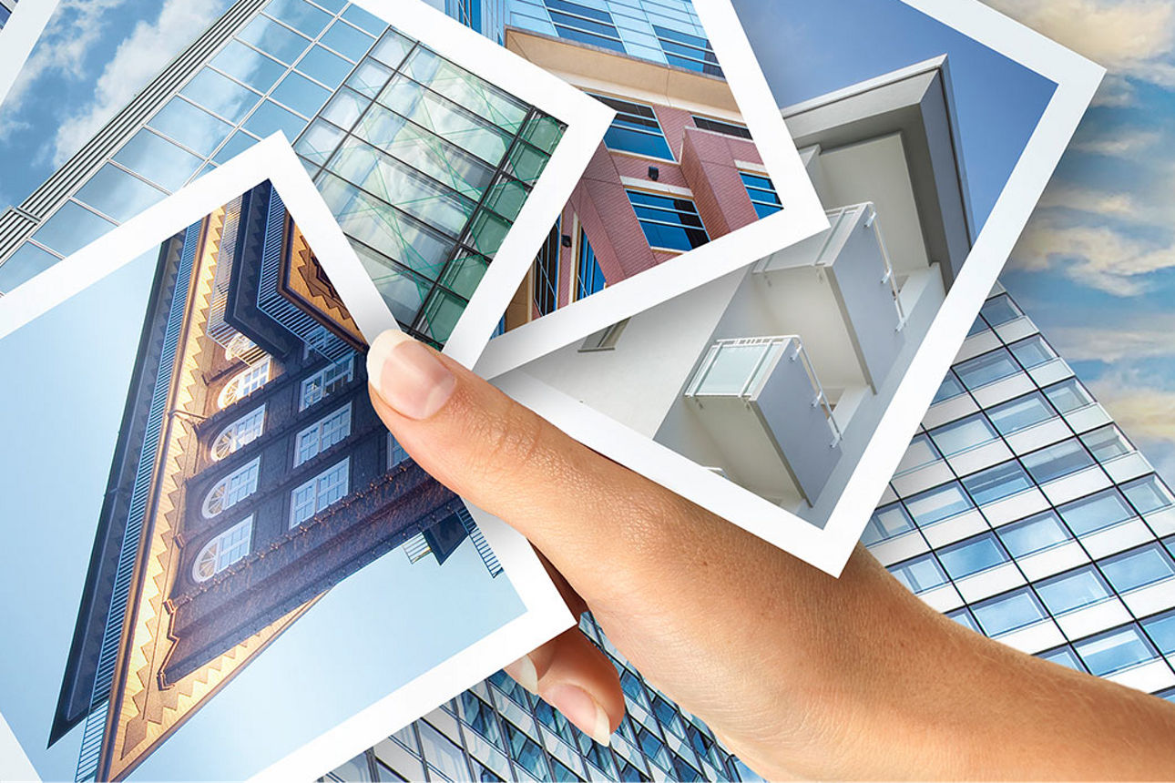Eine Hand mit Fotos verschiedener moderner Gebäude, im Hintergrund die Glasfassade eines Hochhauses