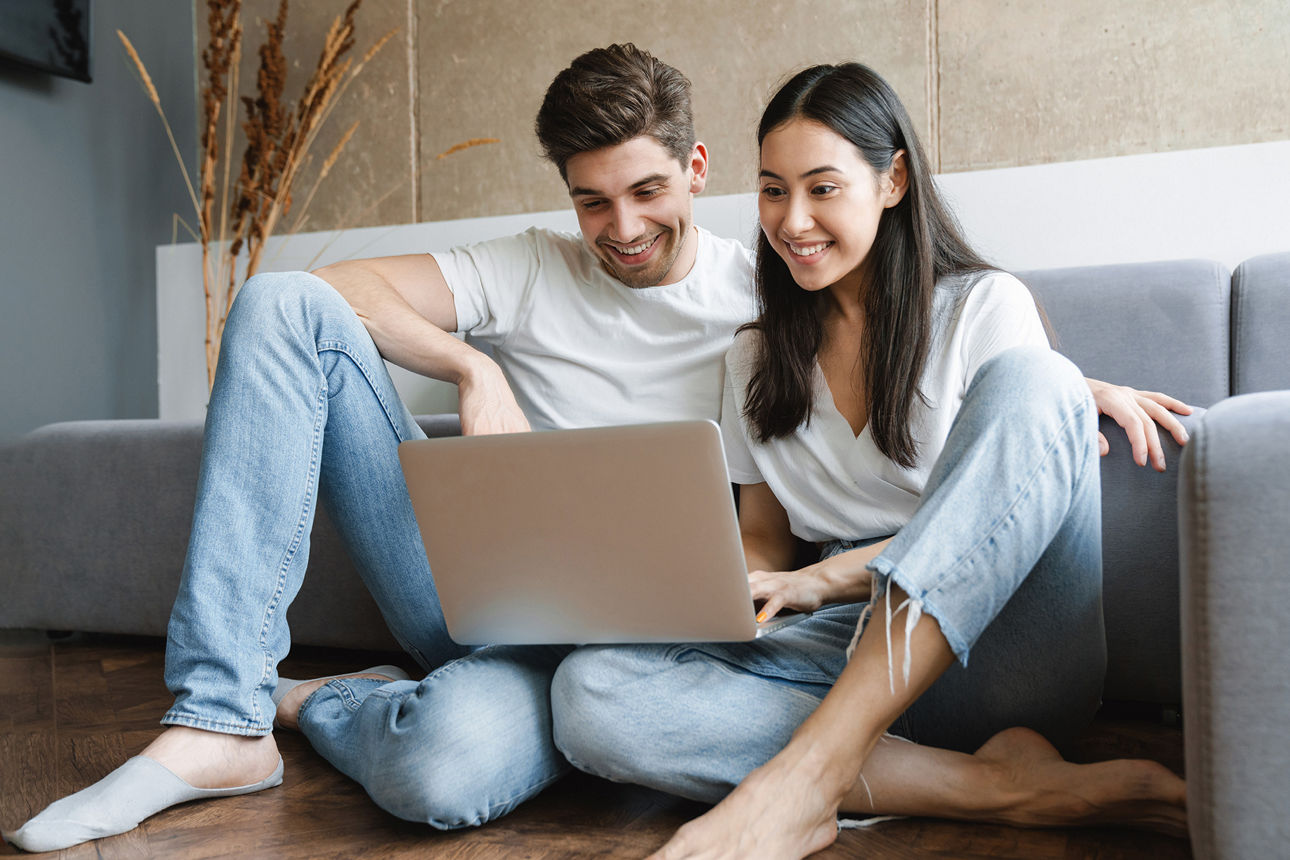 Mann und Frau sitzen auf einem Sofa vor dem Laptop und schauen sich die Online-Geschäftsstelle an