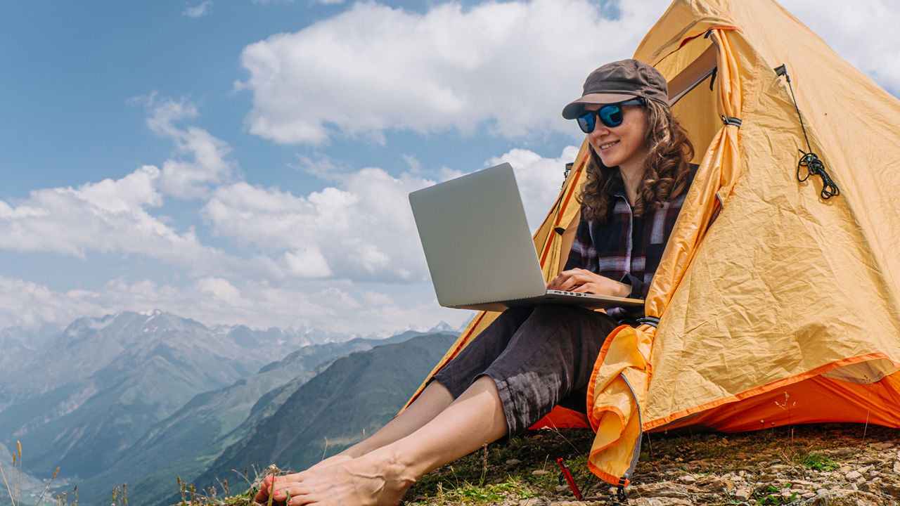 Frau im Zelt auf dem Berg mit Laptop
