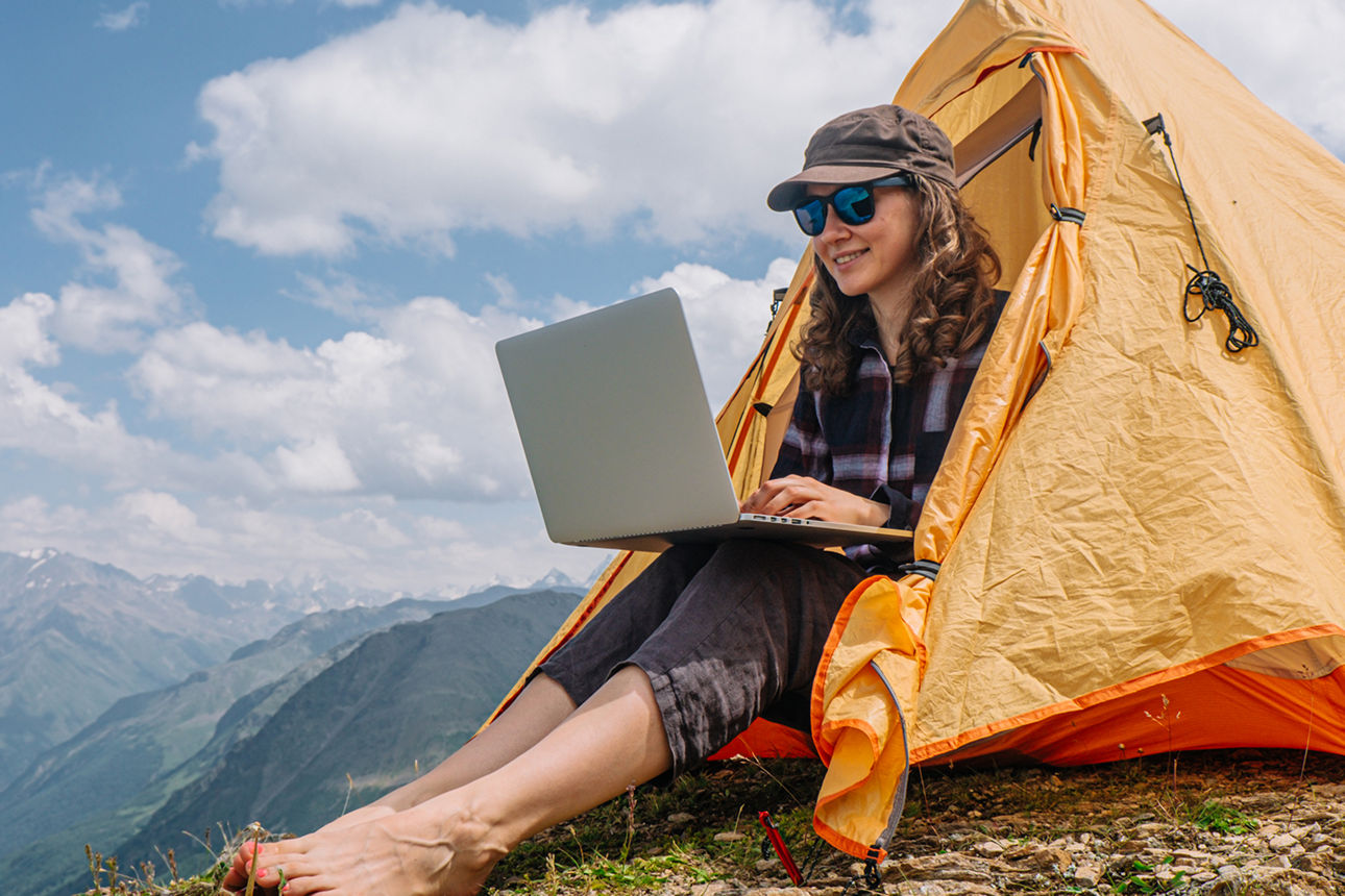 Frau im Zelt in den Bergen mit Laptop