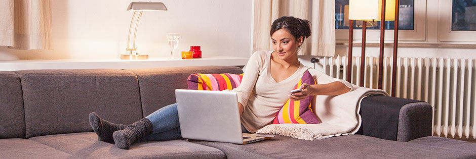 Frau arbeitet auf dem Sofa an einem Lapop