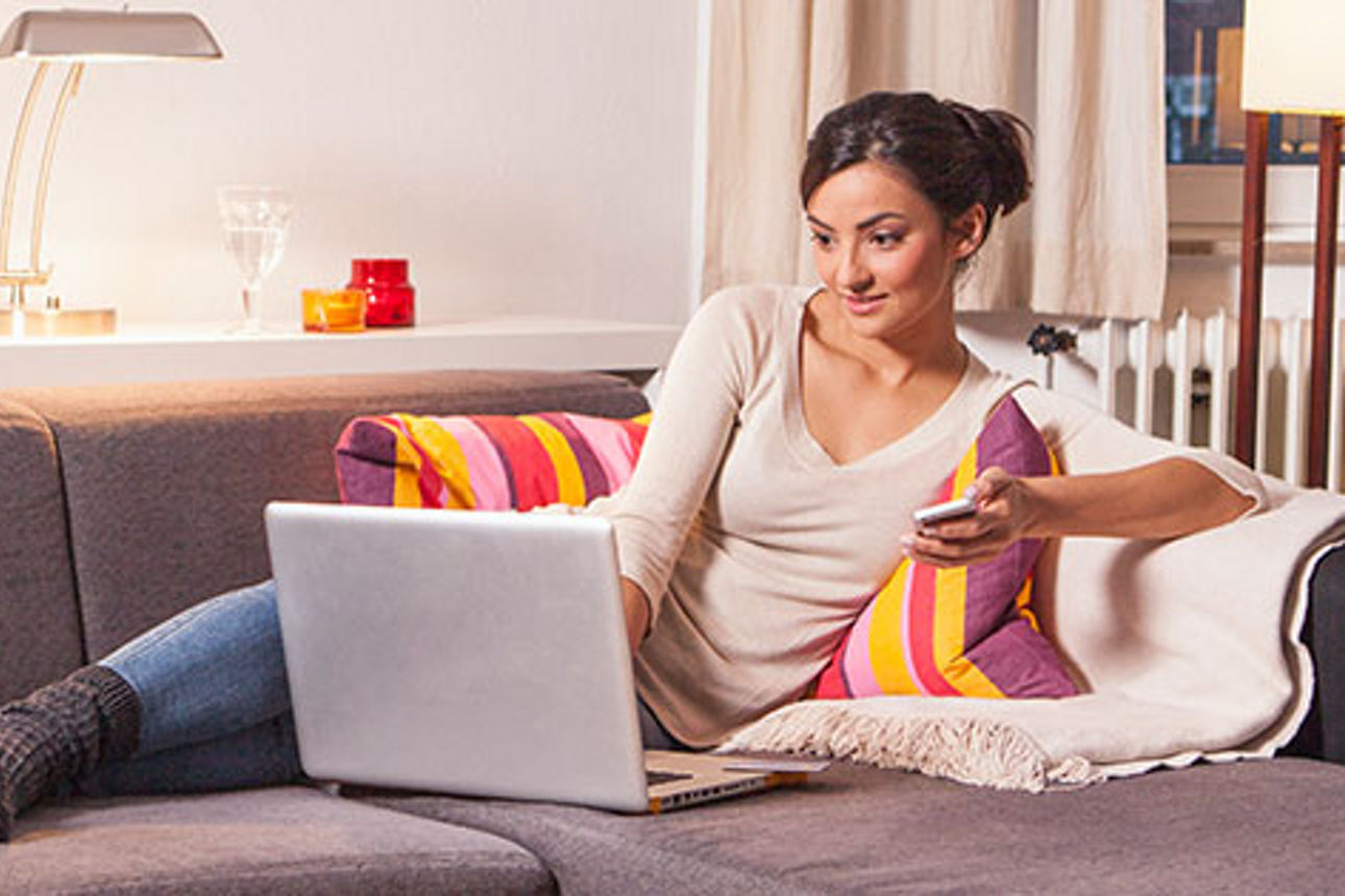 Frau arbeitet auf dem Sofa an einem Lapop