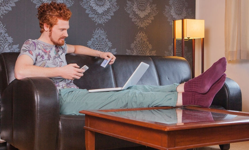 Ein Mann sitzt auf der Couch vor seinem Laptop.