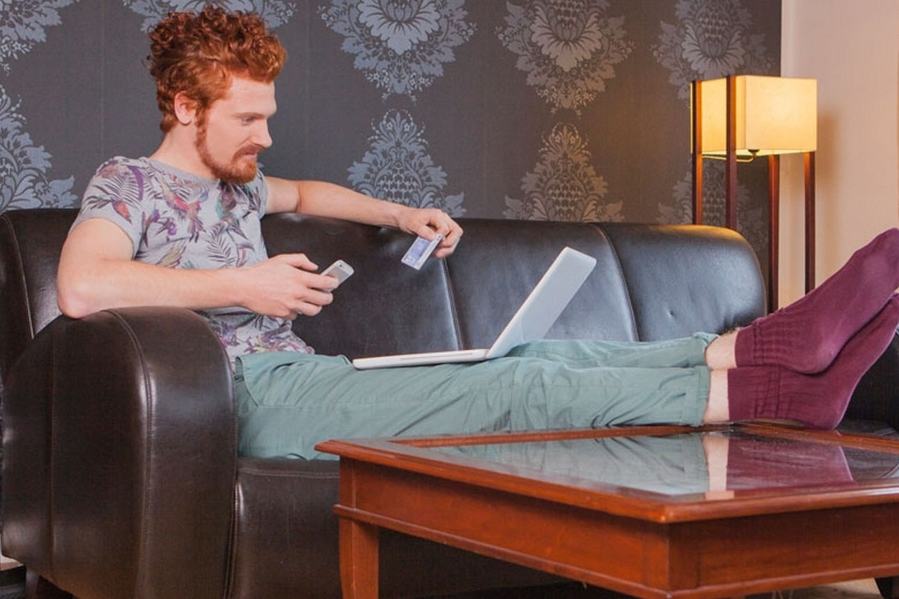 Ein Mann sitzt auf der Couch vor seinem Laptop.