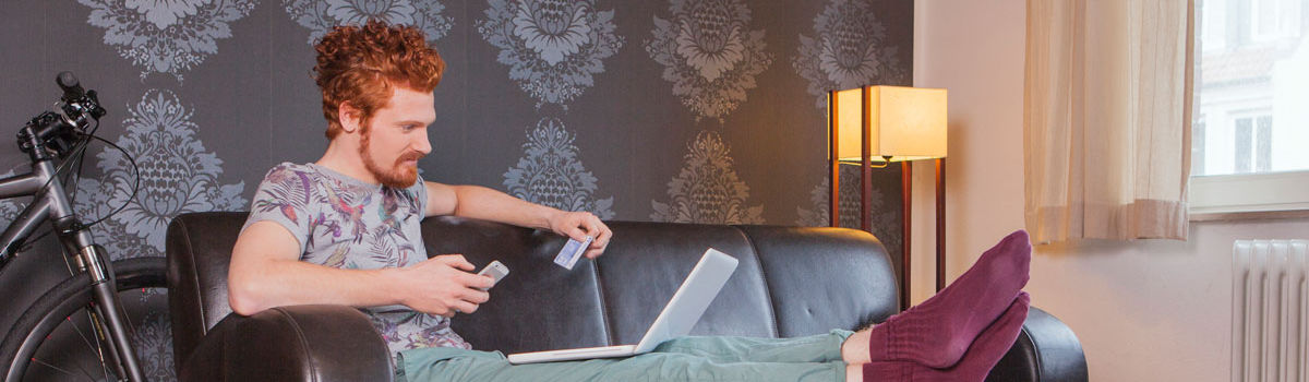 Mann der auf der Couch sitzt und sich mit seinem Smartphone und Ausweis online legitimiert