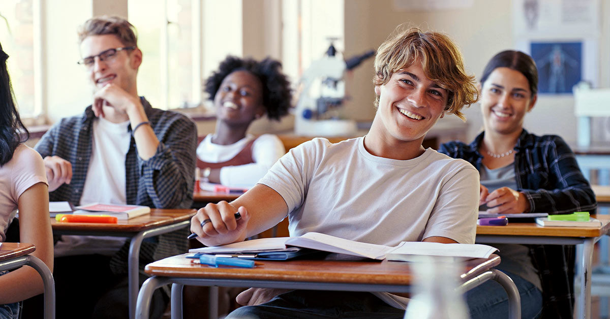 Teenager, 2 Mädchen, 1 Junge gehen zusammen mit Rucksack und Schulunterlagen im Arm