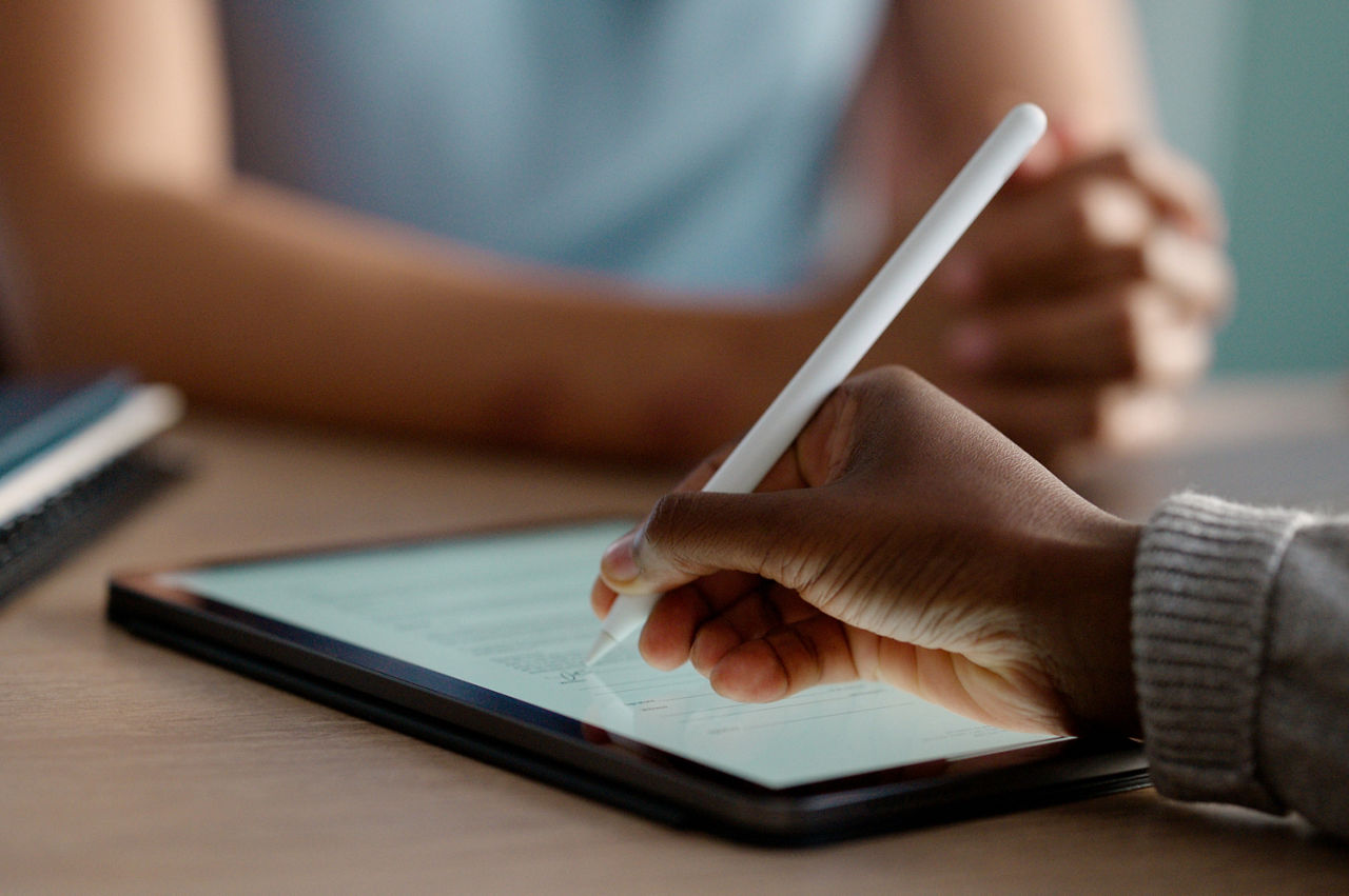 Hands, tablet and onliIm Fokus liegt ein Tablet auf einem Tisch. Eine Hand hält einen Stift und unterschreibt ein digitales Formular auf dem Bildschirm. ne signature for contract meeting with agreement for employment for document, form or collaboration. Businesspeople, internet and partnership in London, digital or paperwork