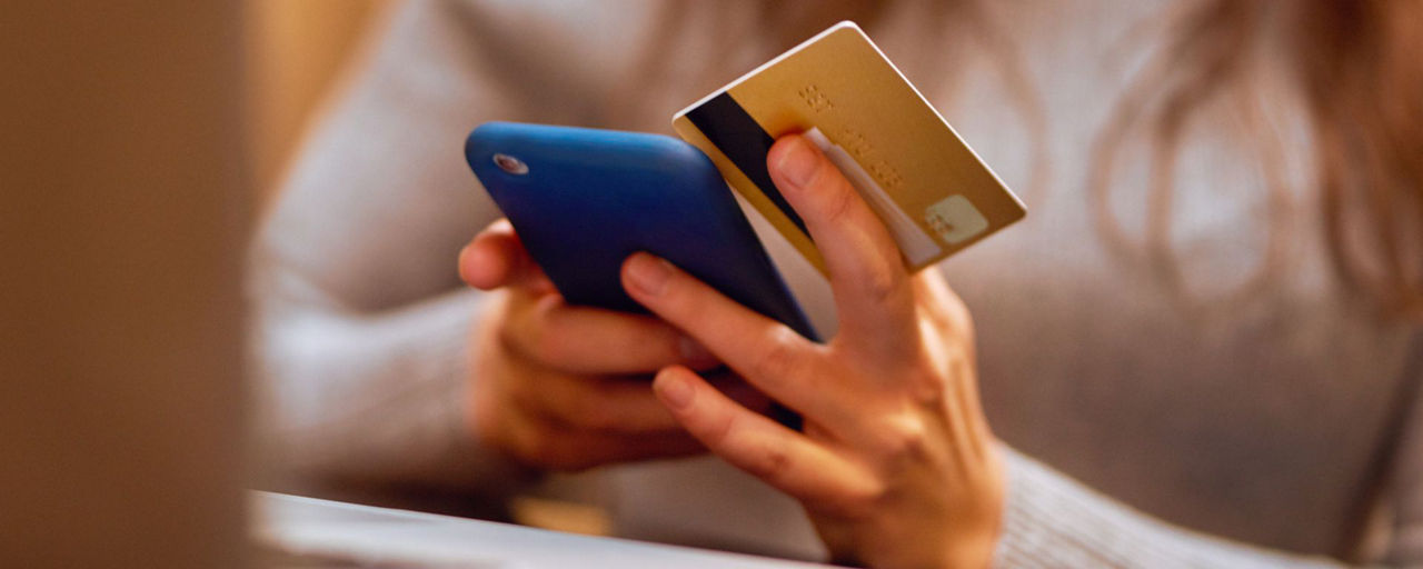 Eine Frau hält ein Smartphone und eine Kreditkarte in der Hand.