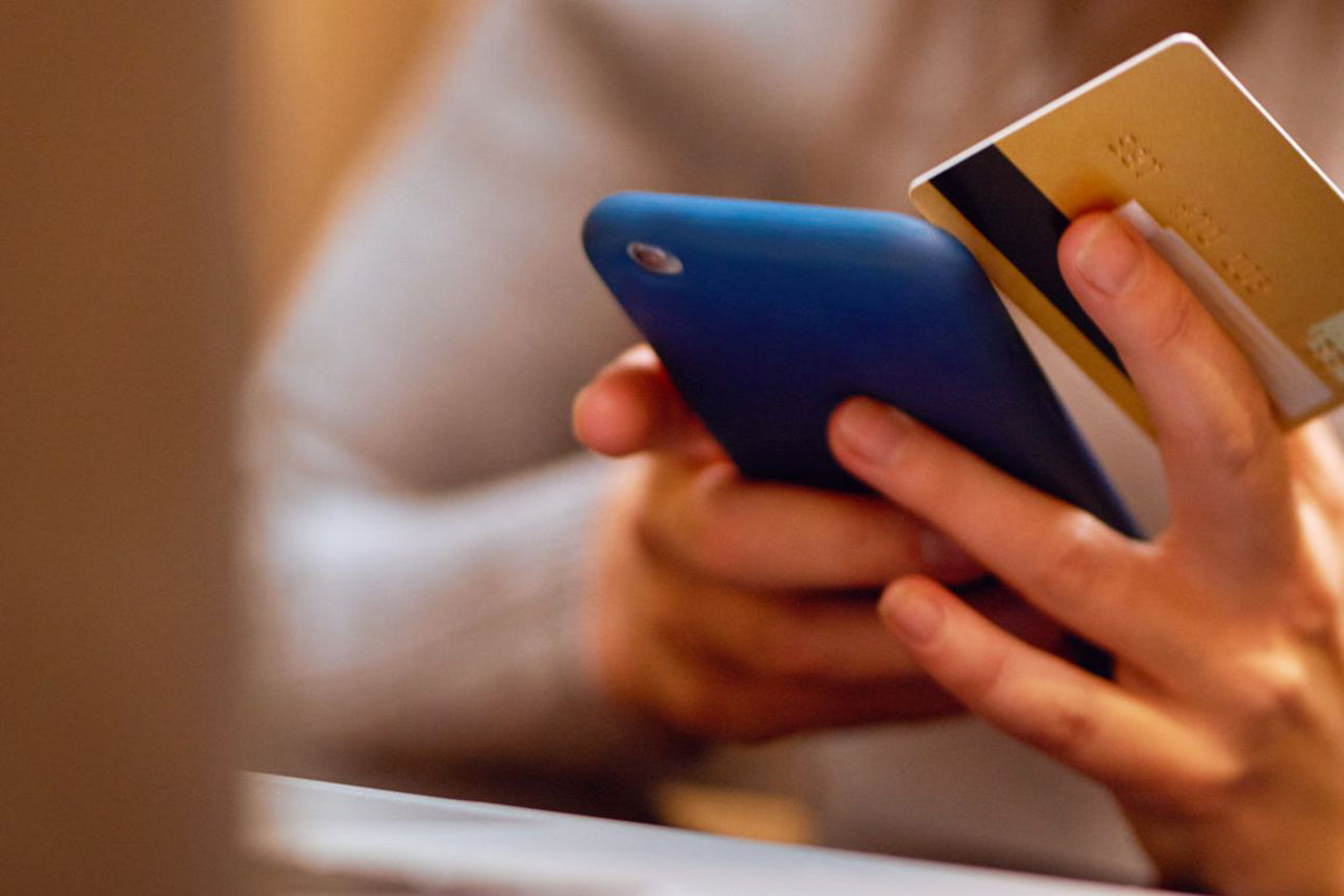 Eine Frau hält ein Smartphone und eine Kreditkarte in der Hand.