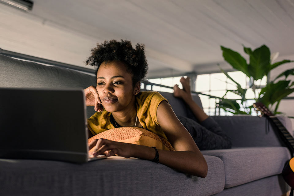 frau liegt auf sofa vor einem laptop
