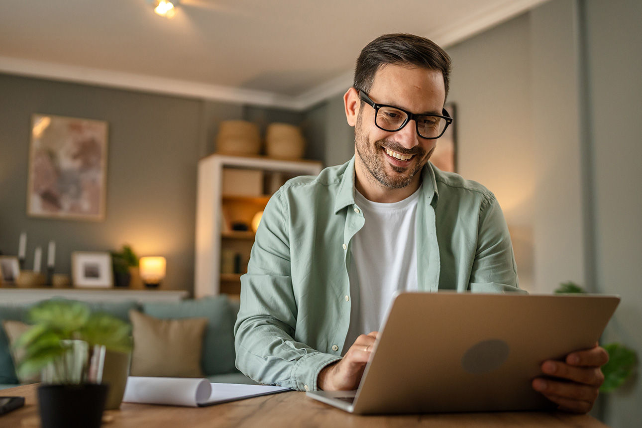 Mann sitzt vor einem Laptop und schaut drauf
