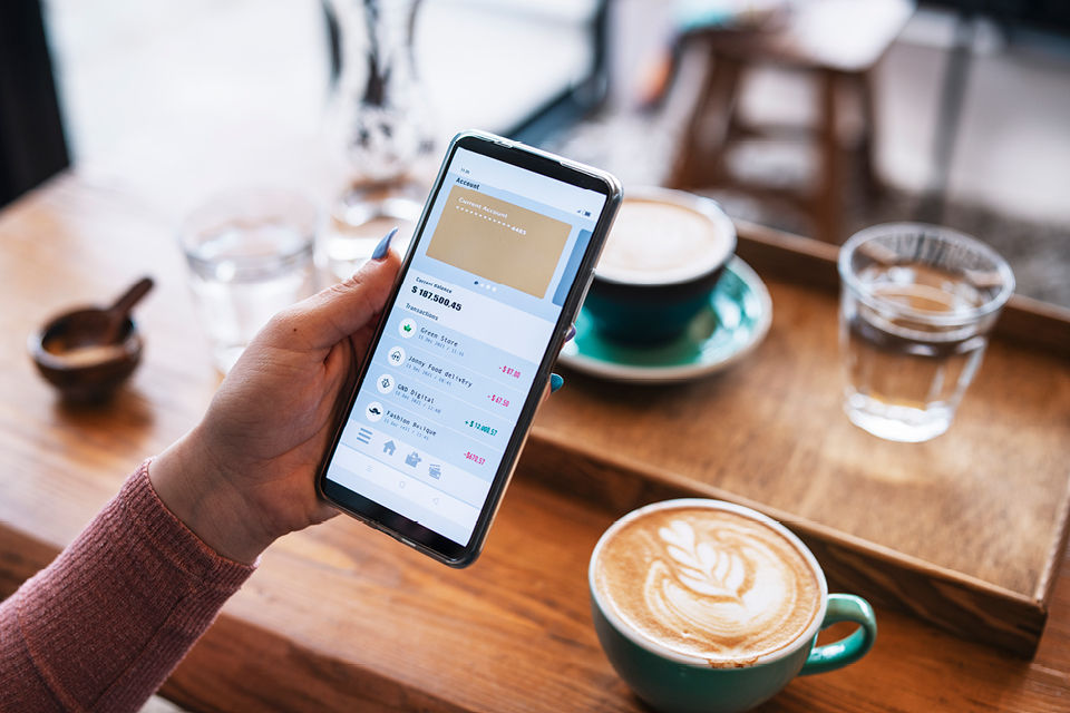 Person checkt in einem Cafe ihre BankingApp