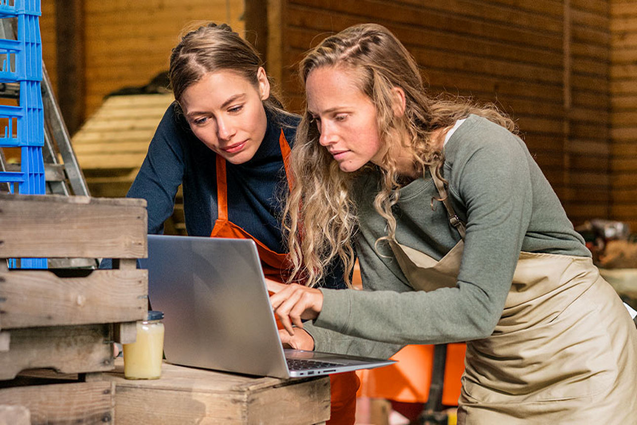 Zwei Frauen sehe in einer Lagerhalle auf einen Laptop