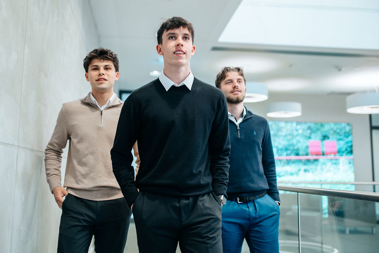 Drei junge Männer gehen lässig auf die Kamera zu.