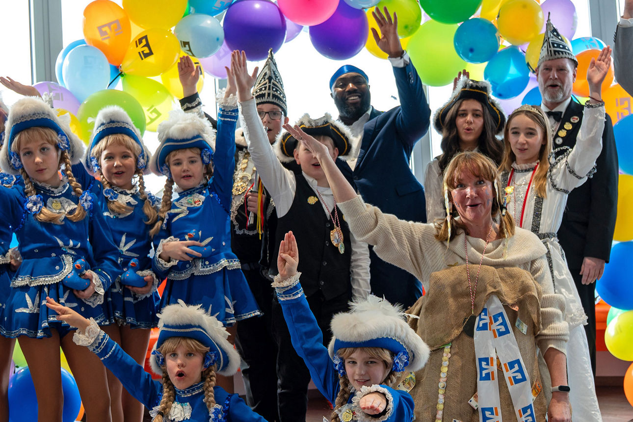 Kinder in bunten Kostümen feiern fröhlich mit Luftballons und Konfetti.