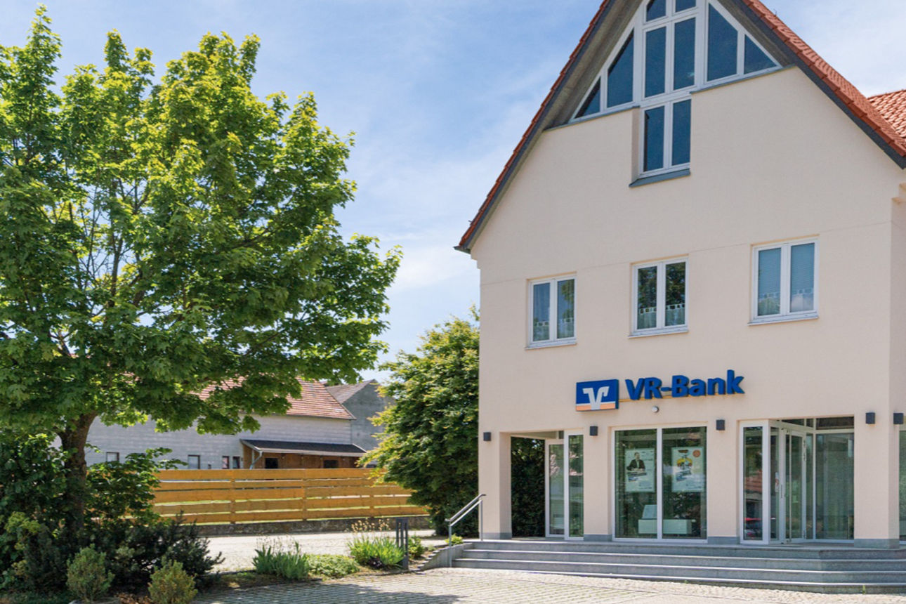 Man sieht das Gebäude der Bankstelle in Burgharting von der Straße aus.