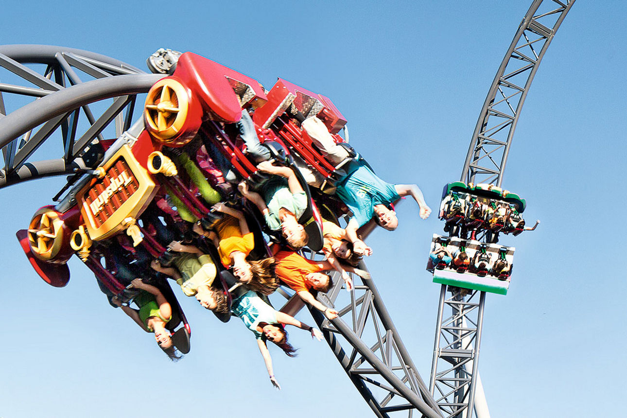 Achterbahn mit Fahrgästen in rasanter Kurve eines Freizeitparks.