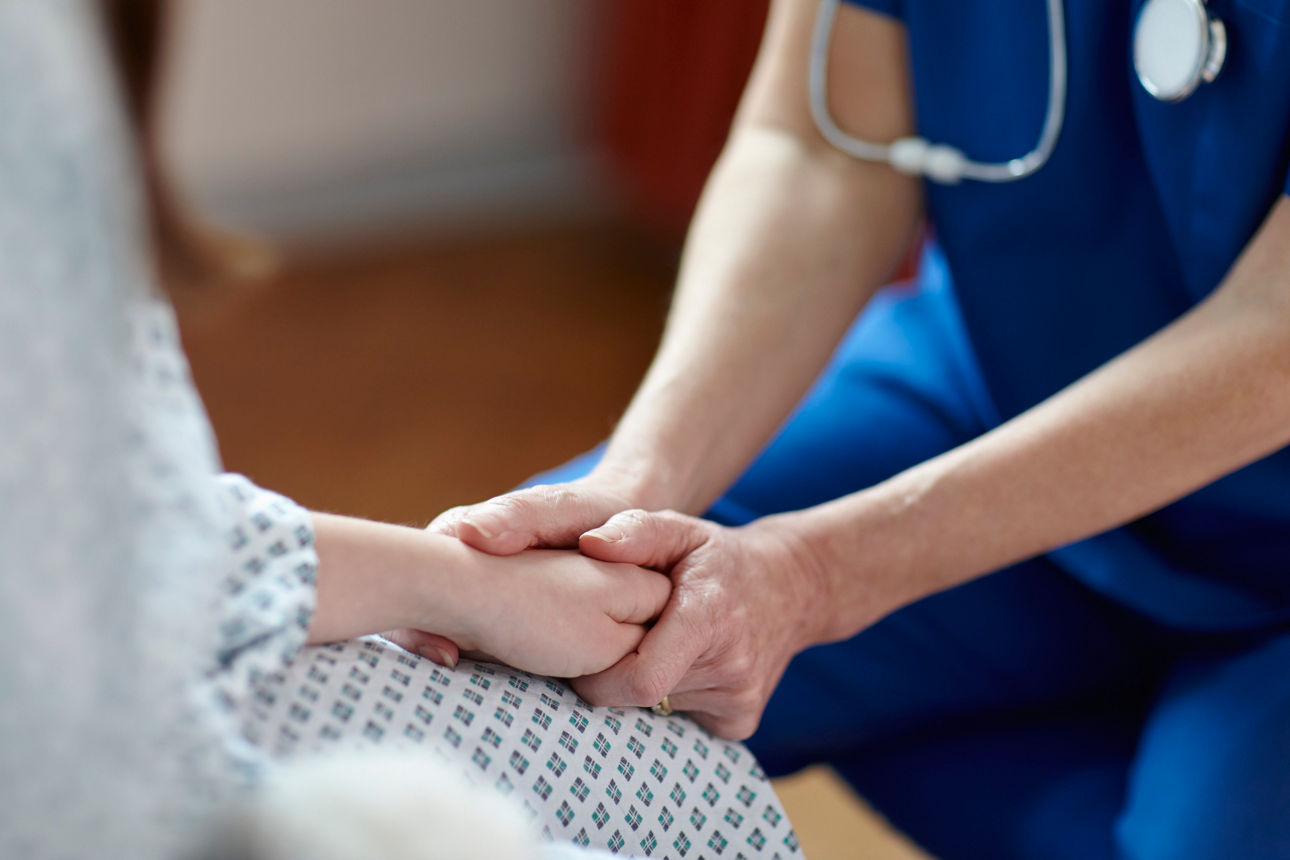 Pflegepersonal im Krankenhaus hält die Hand eines Patienten