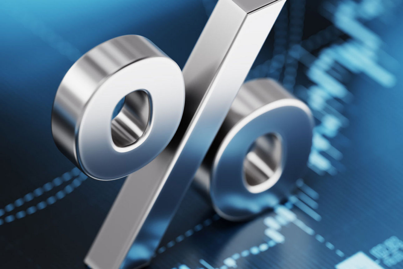 Metallisches Prozentzeichen vor digitalem Finanzdiagramm.