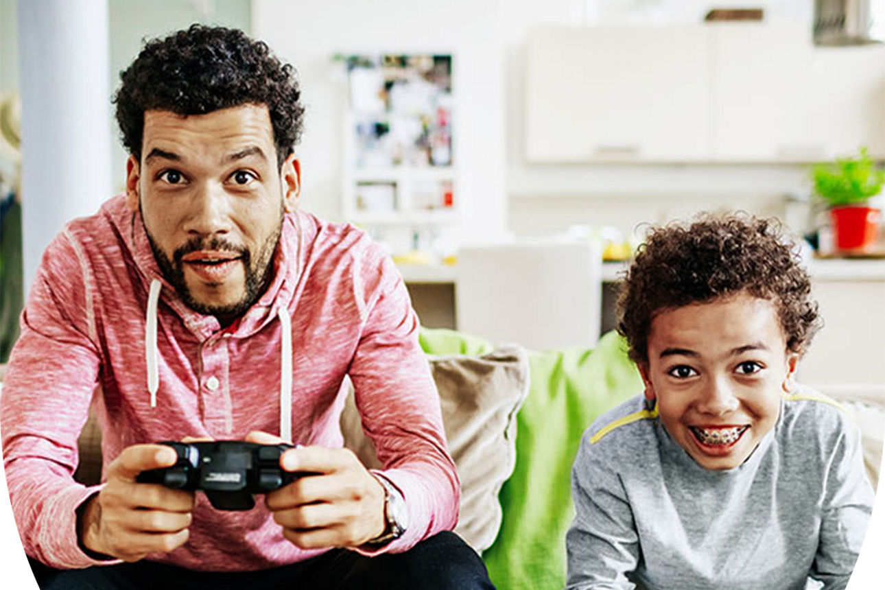 Vater und Sohn sitzen nebeneinander auf der Couch und spielen ein Videospiel