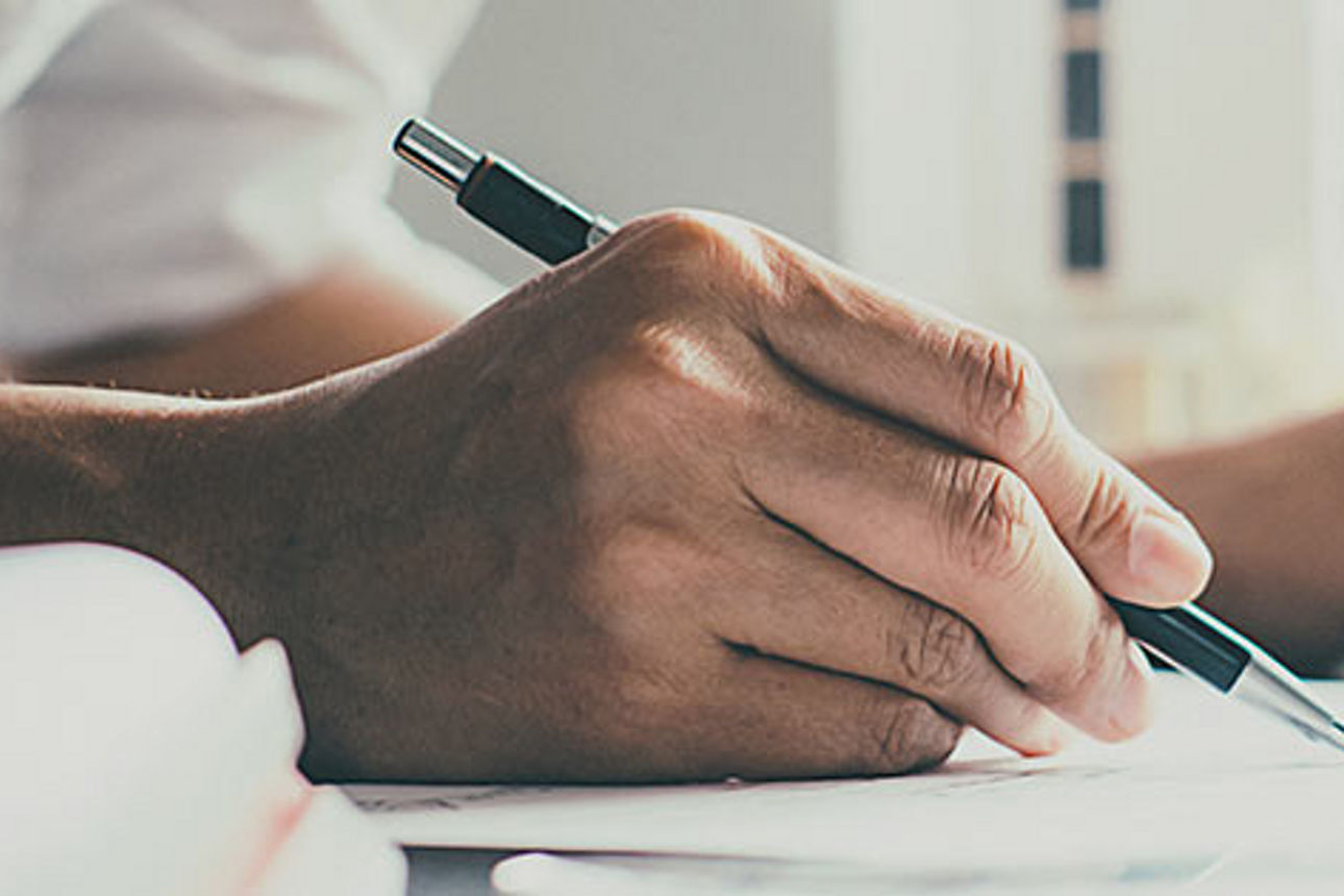 Die Hand einer Frau, die einen mechanischen Stift hält, während sie mit der anderen Hand auf einem Tablet tippt