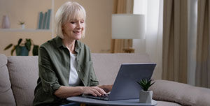 Frau mit grauem Haar arbeitet am Laptop