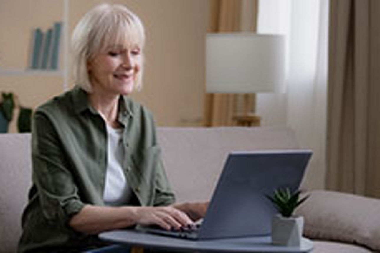 Frau mit grauem Haar arbeitet am Laptop