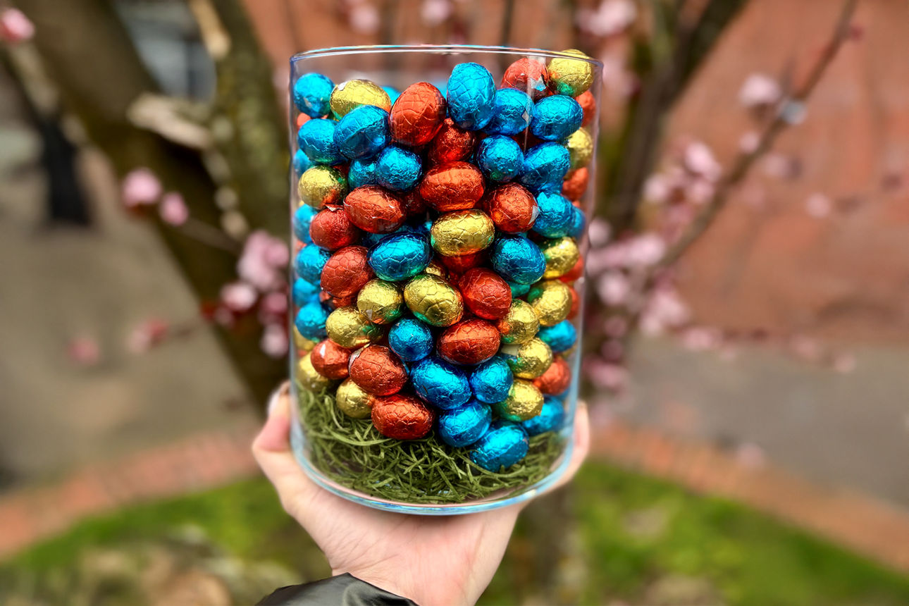 Viele bunte Schokoladen-Eier in einem Glasgefäß.