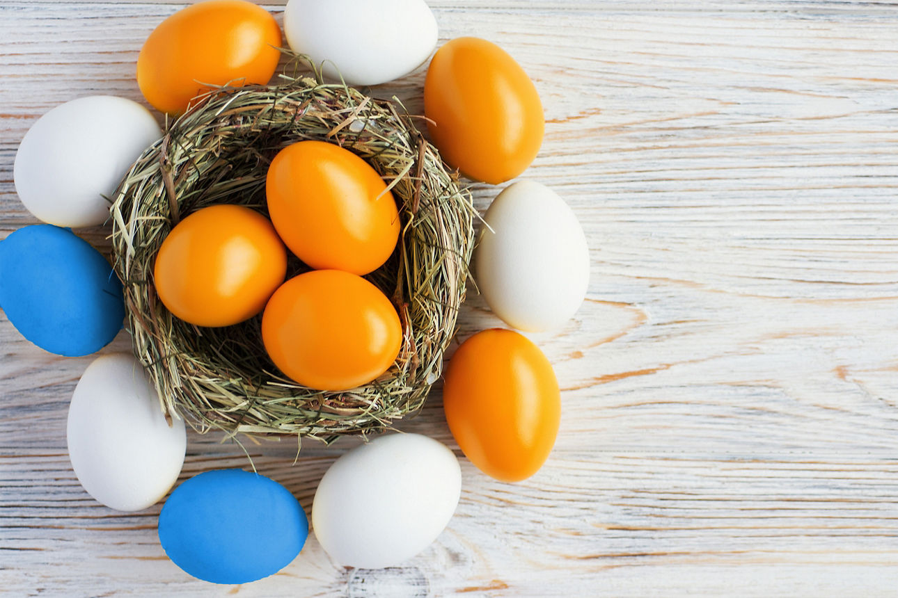 Osternest aus Stroh mit farbigen Eiern