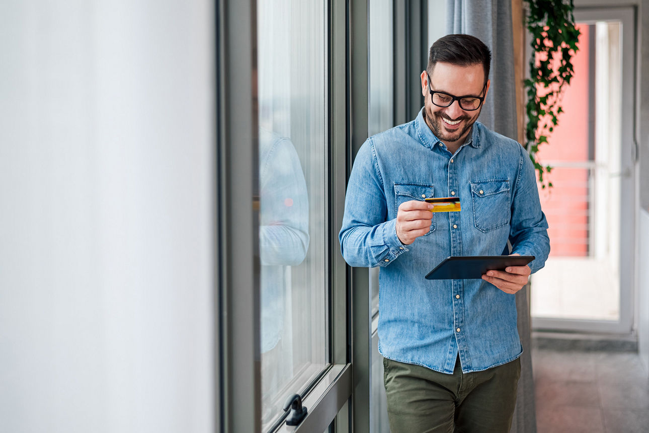 Mann hält eine Debitkarte und ein Tablet in der Hand
