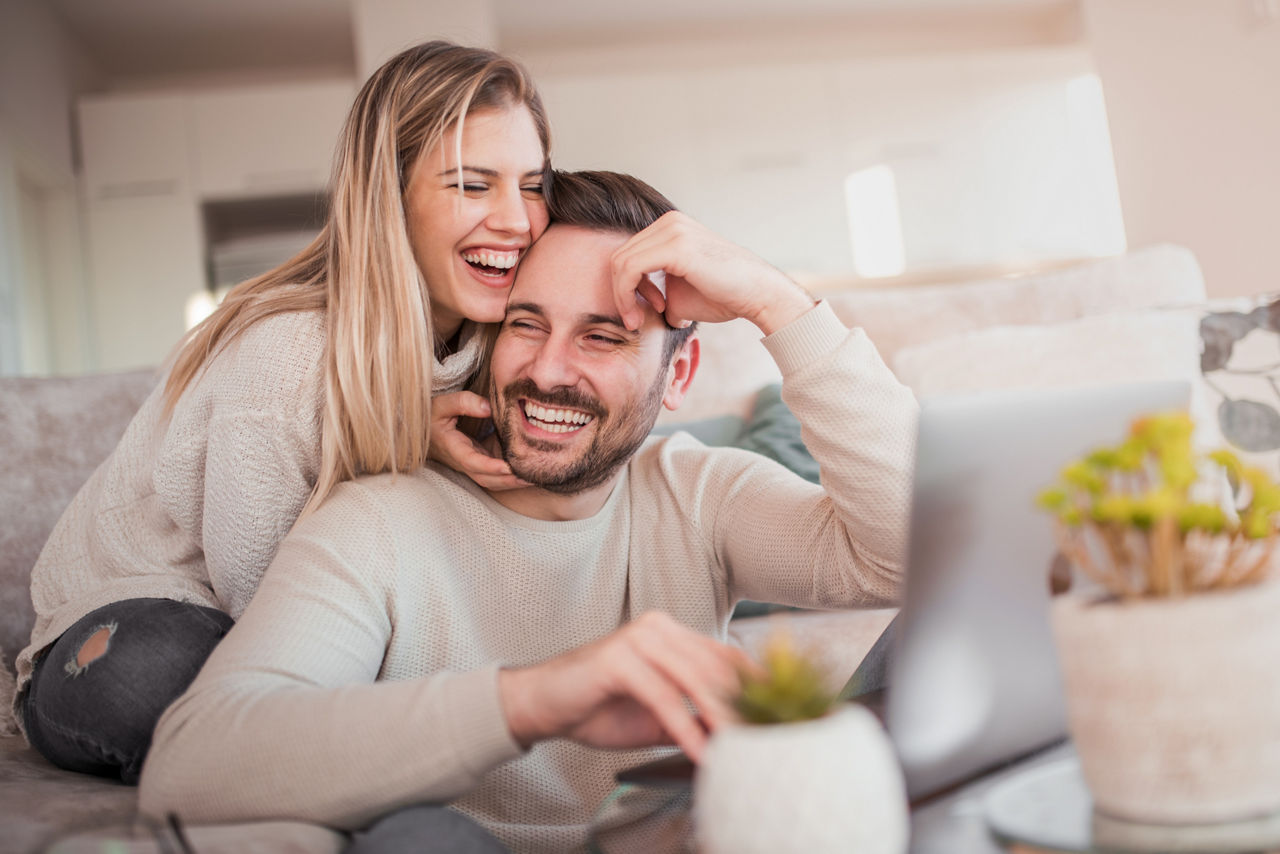 Ehepaar im Wohnzimmer lacht miteinander