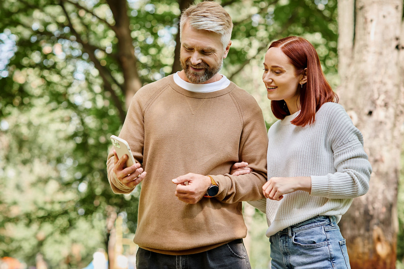 Ein Paar steht im Park und schaut auf ein Smartphone