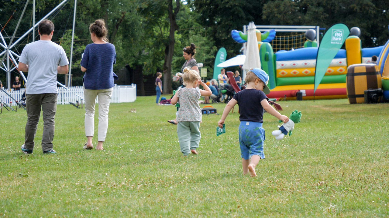 Fotografie mehrerer Kinder und Eltern, die Spaß am PSD Bank Parksommer haben.