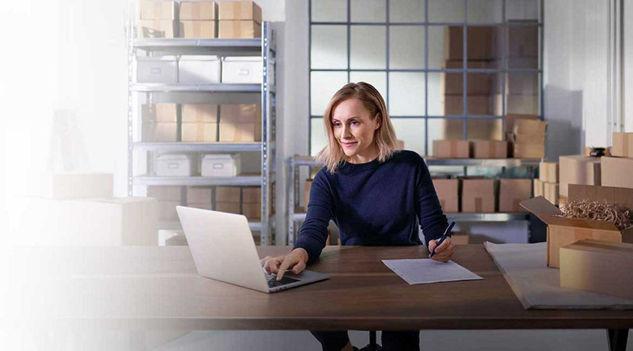 EDEKA-Geschäftskonto Frau sitzt am Schreibtisch und tippt am Laptop