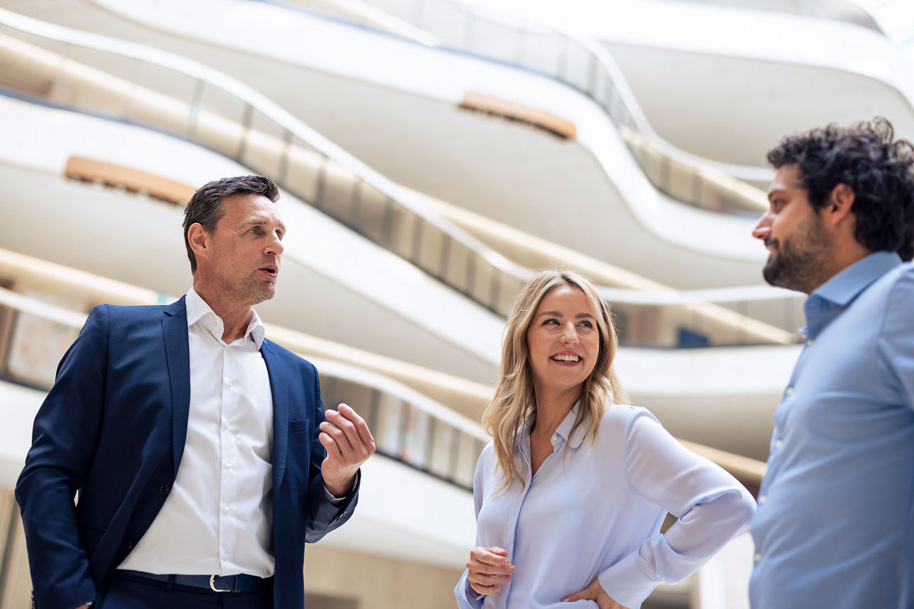 Eine Frau und zwei Kollegen besprechen in der Lobby die nächsten strategischen Schritte